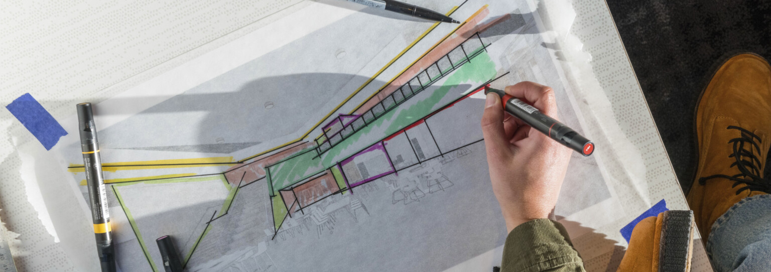 overhead view of woman drawing on an architectural plan