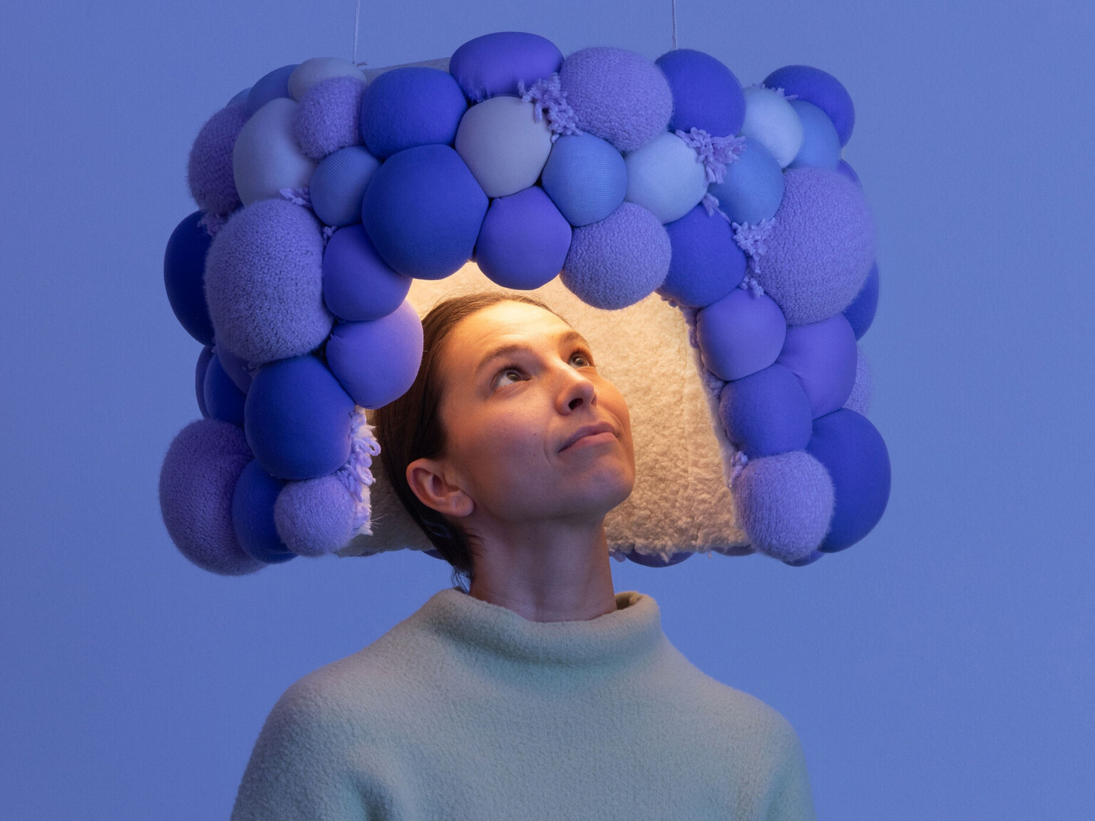 woman standing beneath a sound suppressing design feature; design for neurodiversity and hearing sensitivity, tactile in Venice