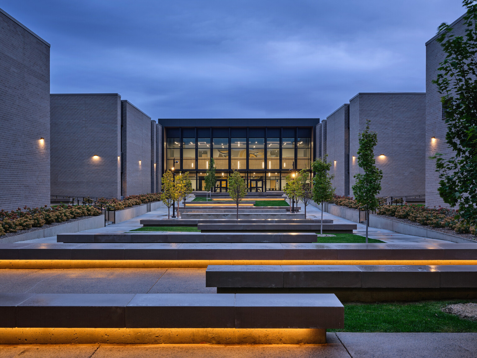 Gretna high school entrance; school at dusk with maze-like benches leading up to the double height entrance with floor to ceiling windows