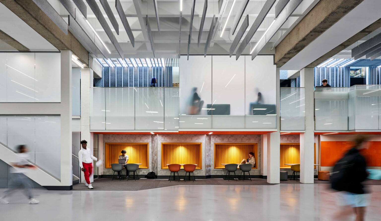 interior school atrium; double height floor with collaboration tables on the first floor, private meeting rooms on the second floor; soft lighting and branding colors adorn the space