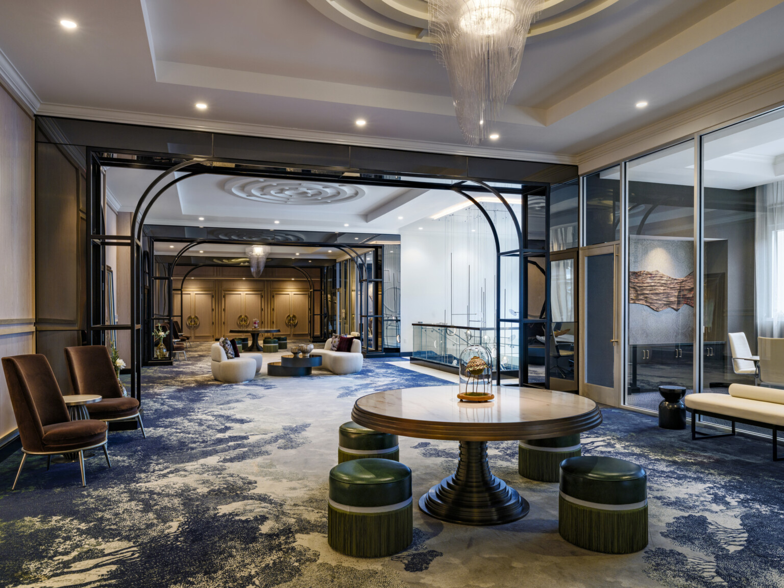The Vanguard Hotel, Autograph Collection hotel lobby; tables and varied seating throughout the space glass walled cut outs separate room to room but open concept flows with natural and chandelier light