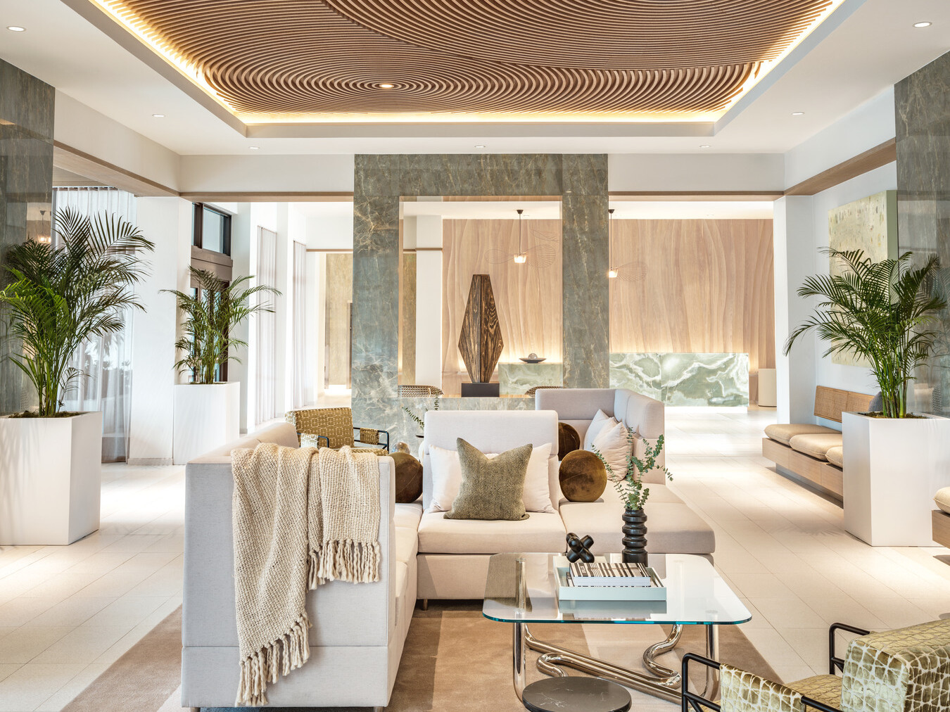 Modern hotel lobby with white couches on natural area rugs, natural wood ceilings, modern green marble sculpture