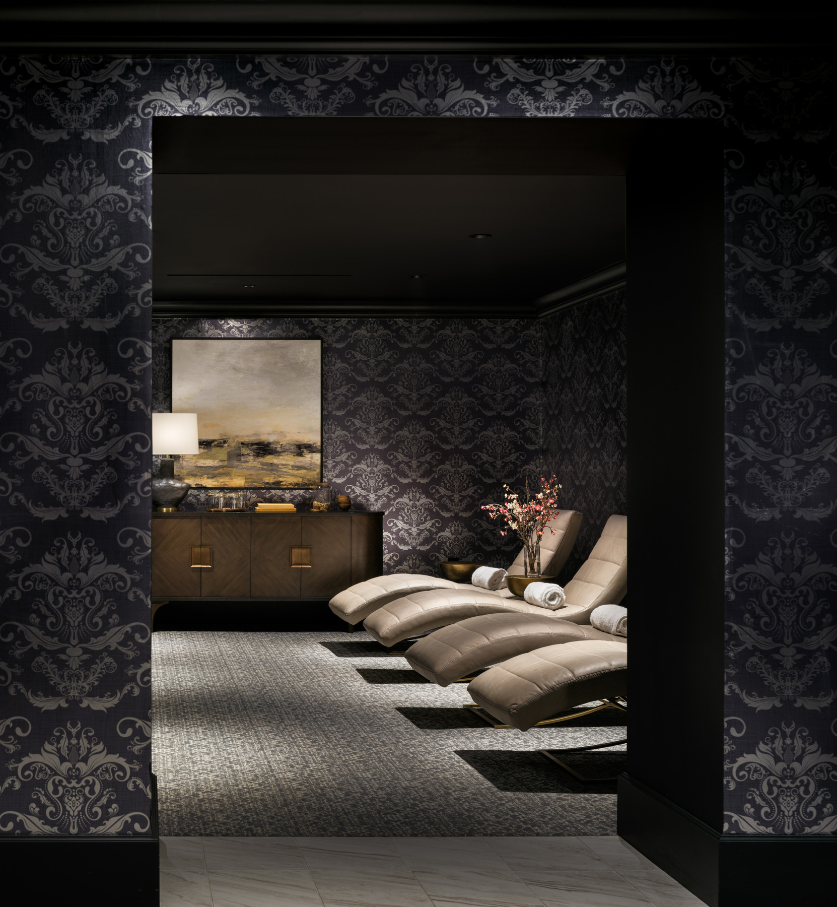 Luxurious spa area with black and silver wallpaper, gold lounge chairs, with bronze furnishings