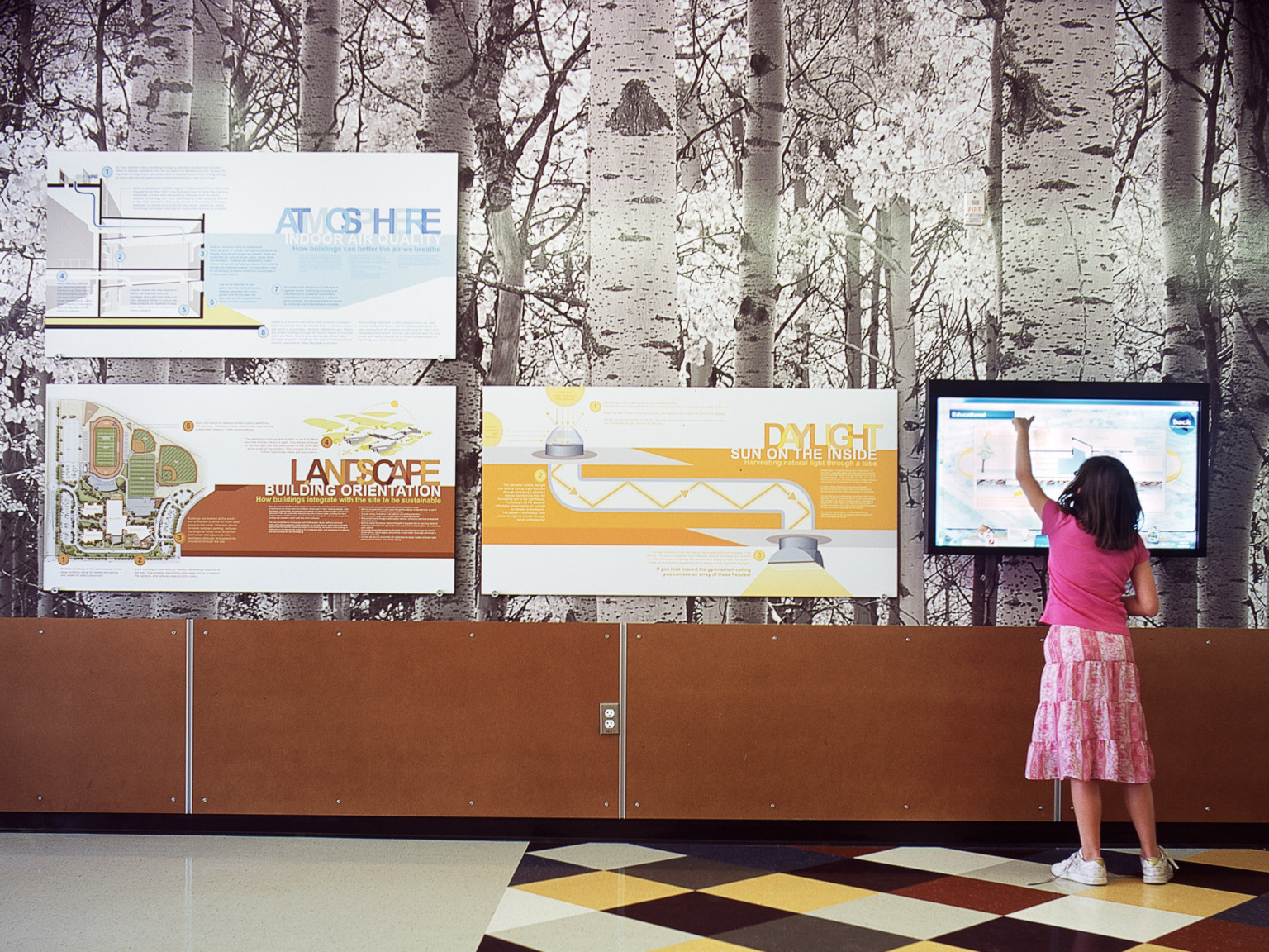 young girl stands at screen on wall with birch tree wallpaper and signage showing the combination of nature with the built environment