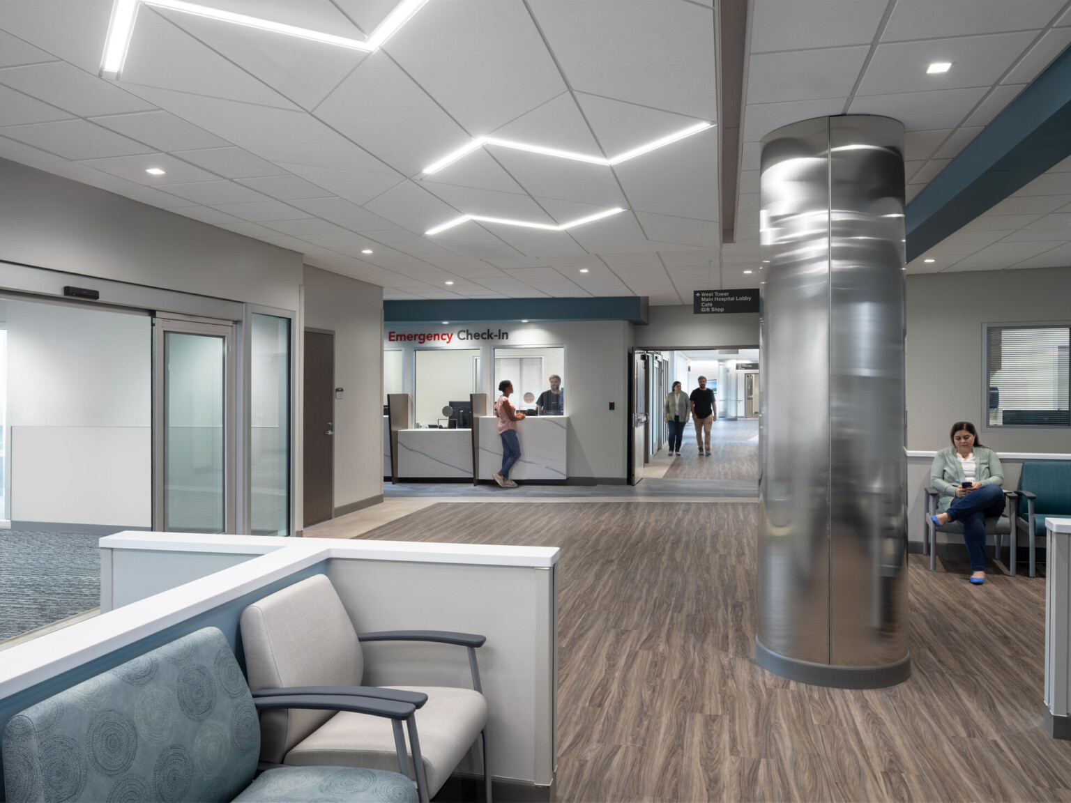Waiting room at UNC Health Blue Ridge;s New Healthcare Pavilion; blue and white seats in the forefront with a reception desk in the back left corner; large shiny mirror like column in the middle of the room