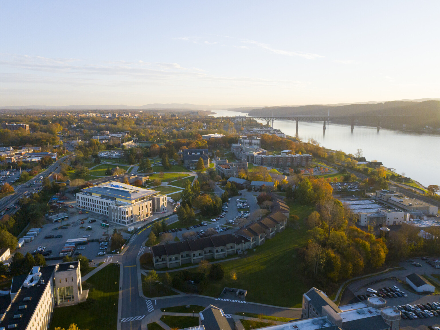 Aerial view of Marist University showing buildings settled in fall colored foliage in front of a river.