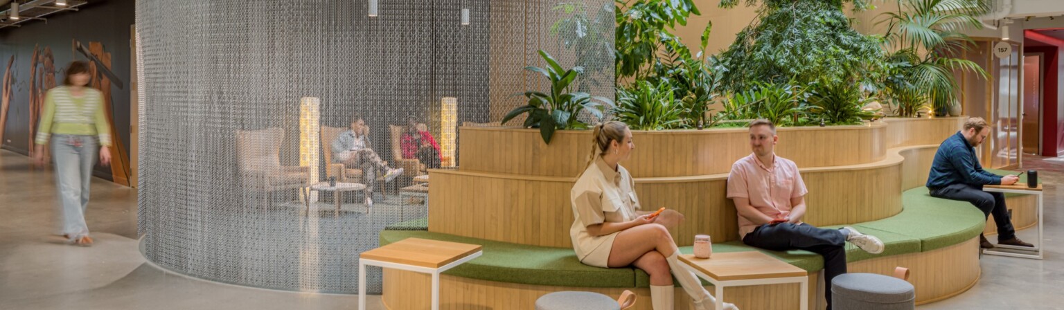 modern workplace with curving bench for conversation, metal curtain for artistic space separation, and biophilic design elements for workplace wellness