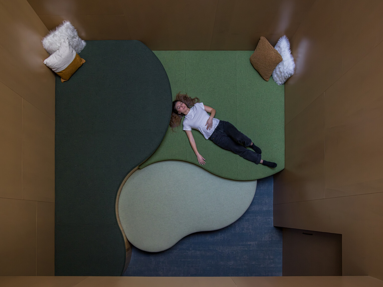 Woman lays in dim, relaxing room with lounging floor space