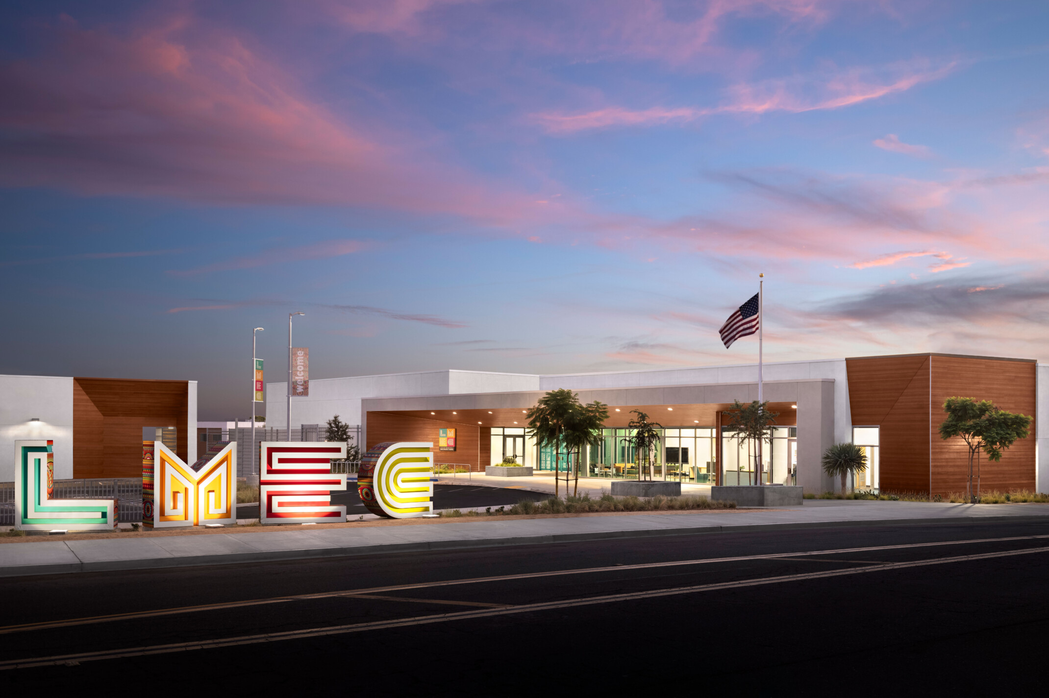 Logan Memorial Education Campus white and wood building viewed across the street; school design with sculpture abstracting the initials LMEC