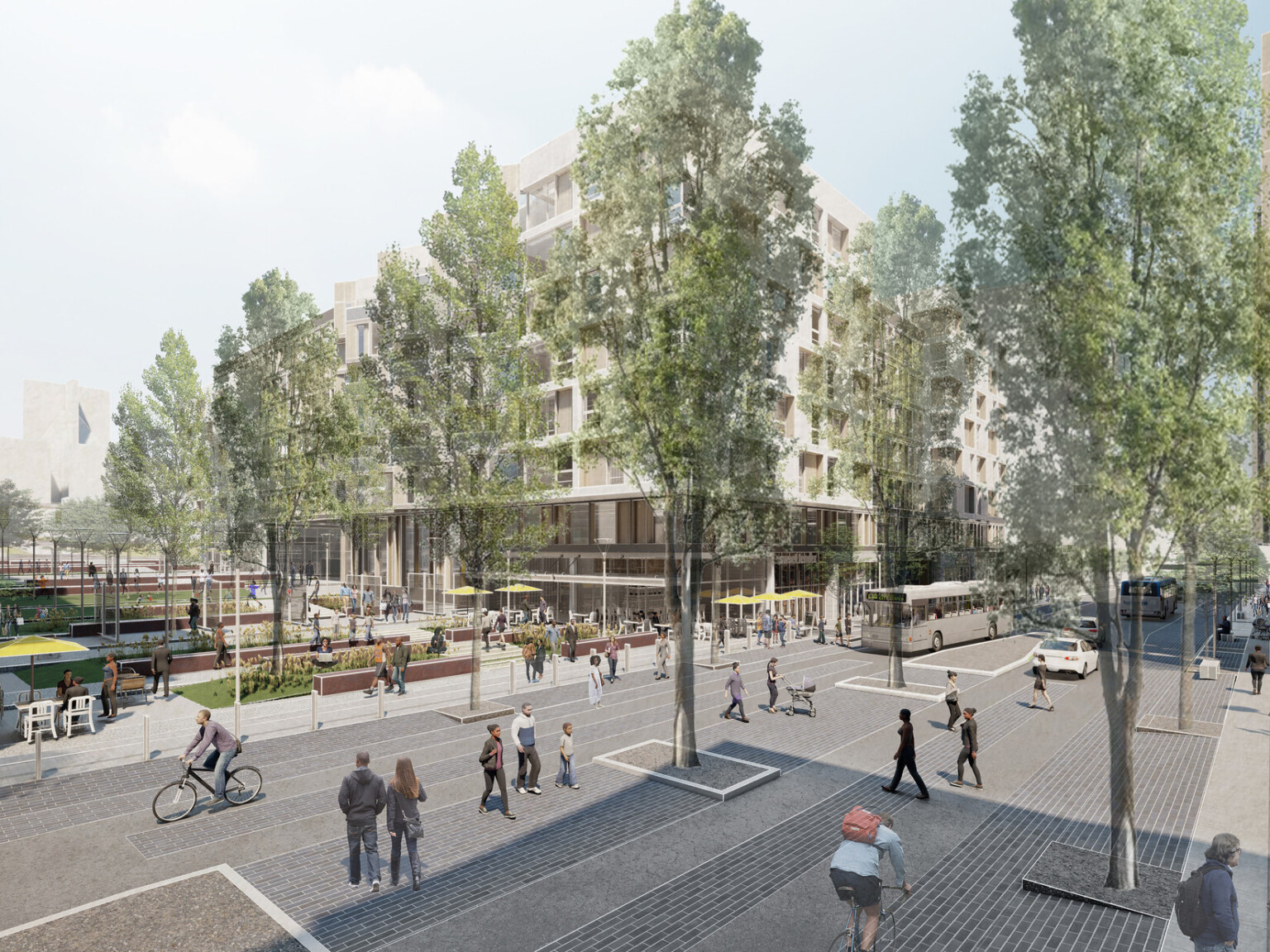 Corner view from across a pedestrian friendly street. Trees along sides of street and median. Outdoor seating and green space