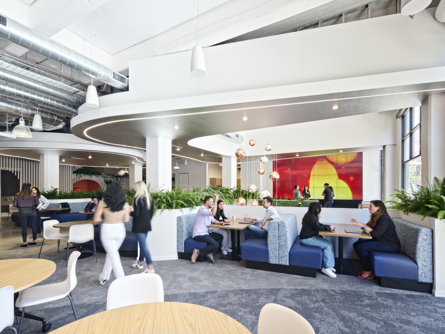 mixed seating with tables and booths in white room with organically shaped white drop ceiling details, metallic chandelier and organic mural