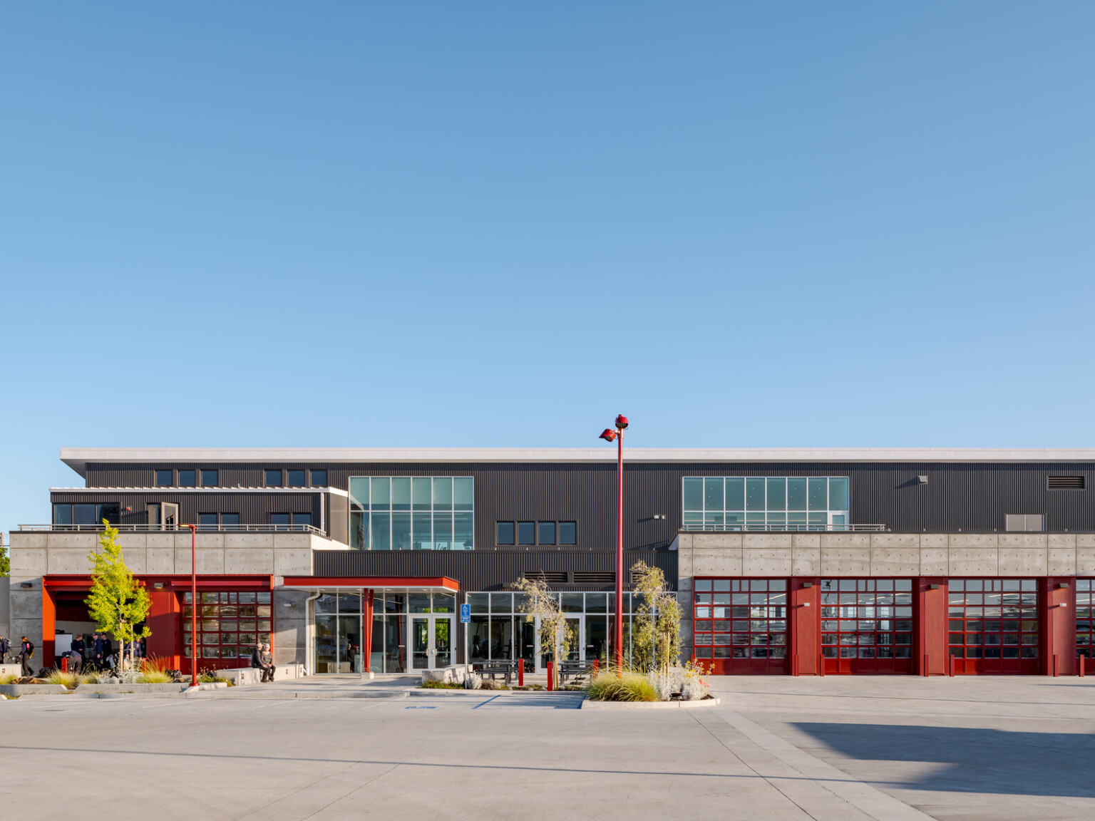 Multistory fire training facility that is black and grey with red accents. Large garage doors to the right of the building
