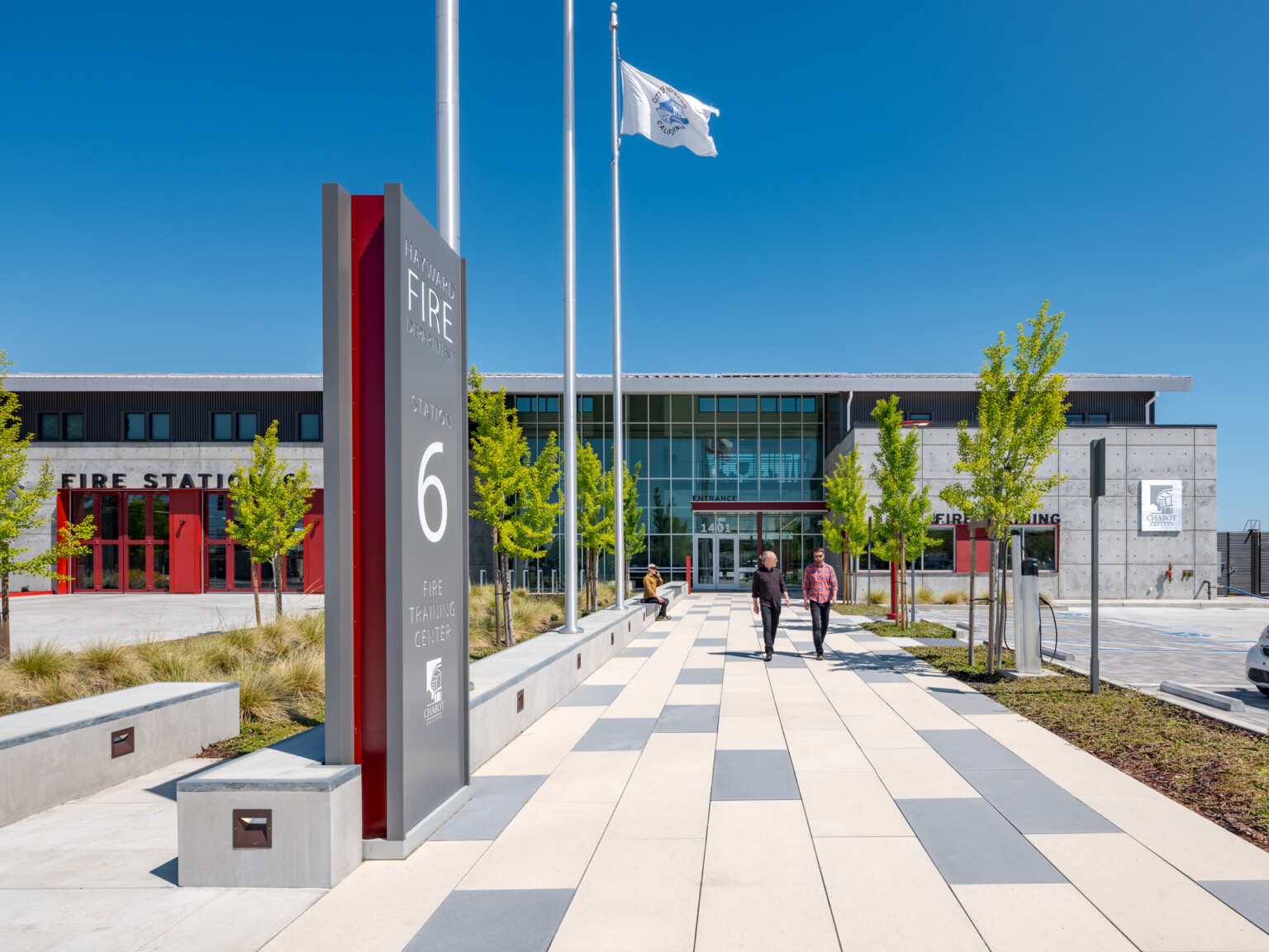 Exterior of the Hayward Fire Department building. Multistory grey building with red accents with a grey and white walkway leading to the front doors