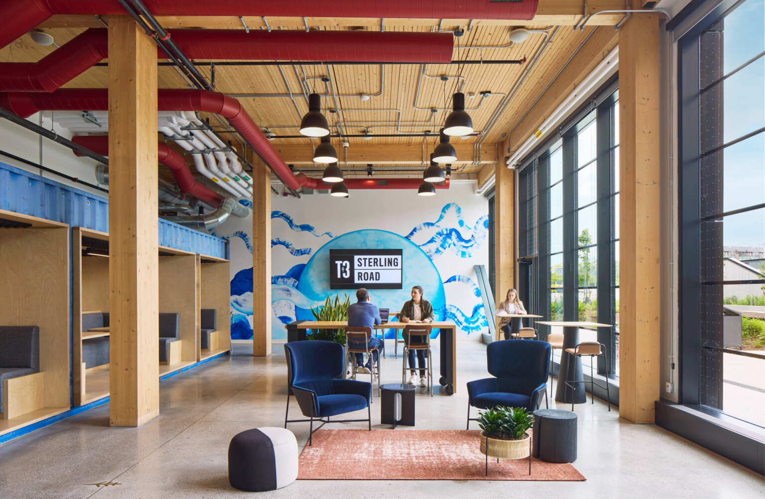 interior design of a mass timber building in toronto; two people working at a high top table with a large mural wall in the back; dlr group design