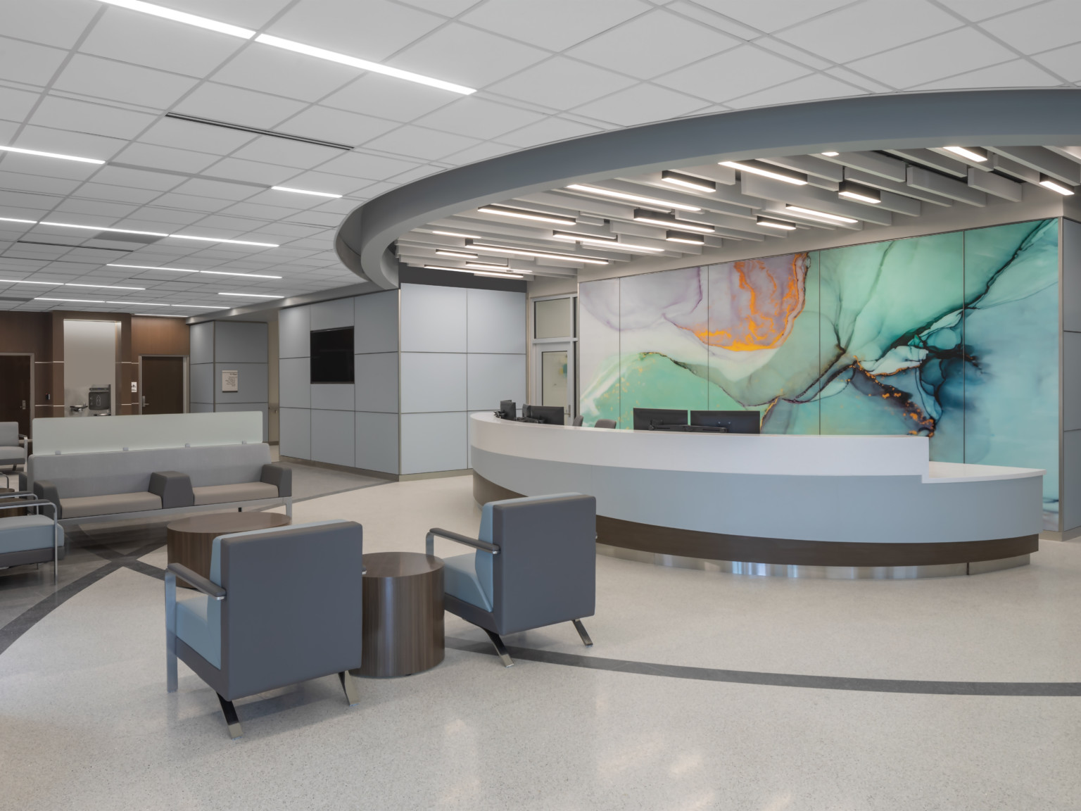 Waiting area lobby with long rounded reception desk in front of marbled wall mural in green with gold and purple accents