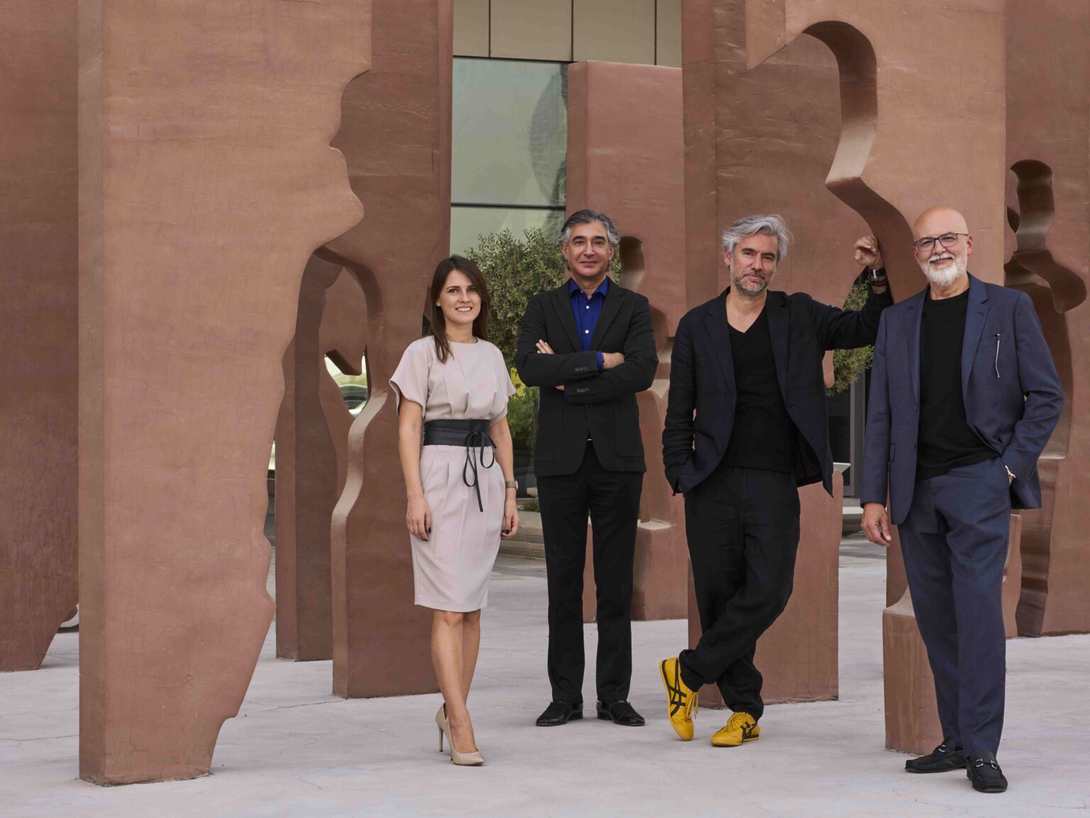 4 people from DLR Group Dubai studio standing in an architectural, sculptural terracotta art piece