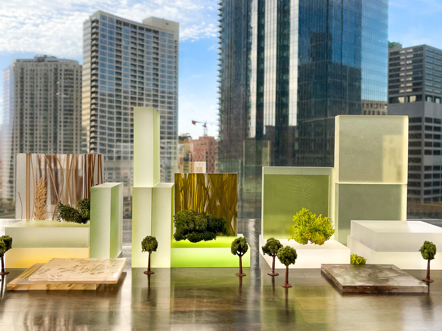 green toned abstract clear models of building with scale trees in front of window, view of high risesgreen toned abstract clear models of building with scale trees in front of window, view of high rises
