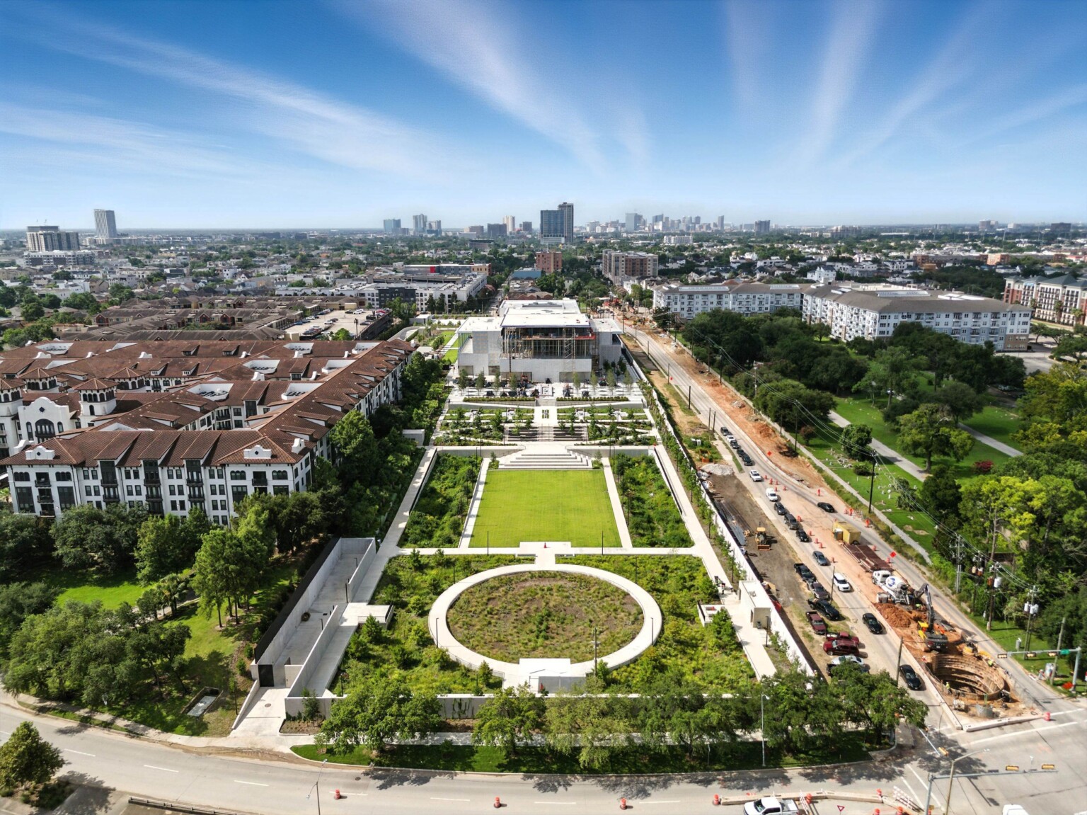 An aerial view looking south highlights the lawns, terraces, and gardens of the Ismaili Center Houston, with the building and its large verand