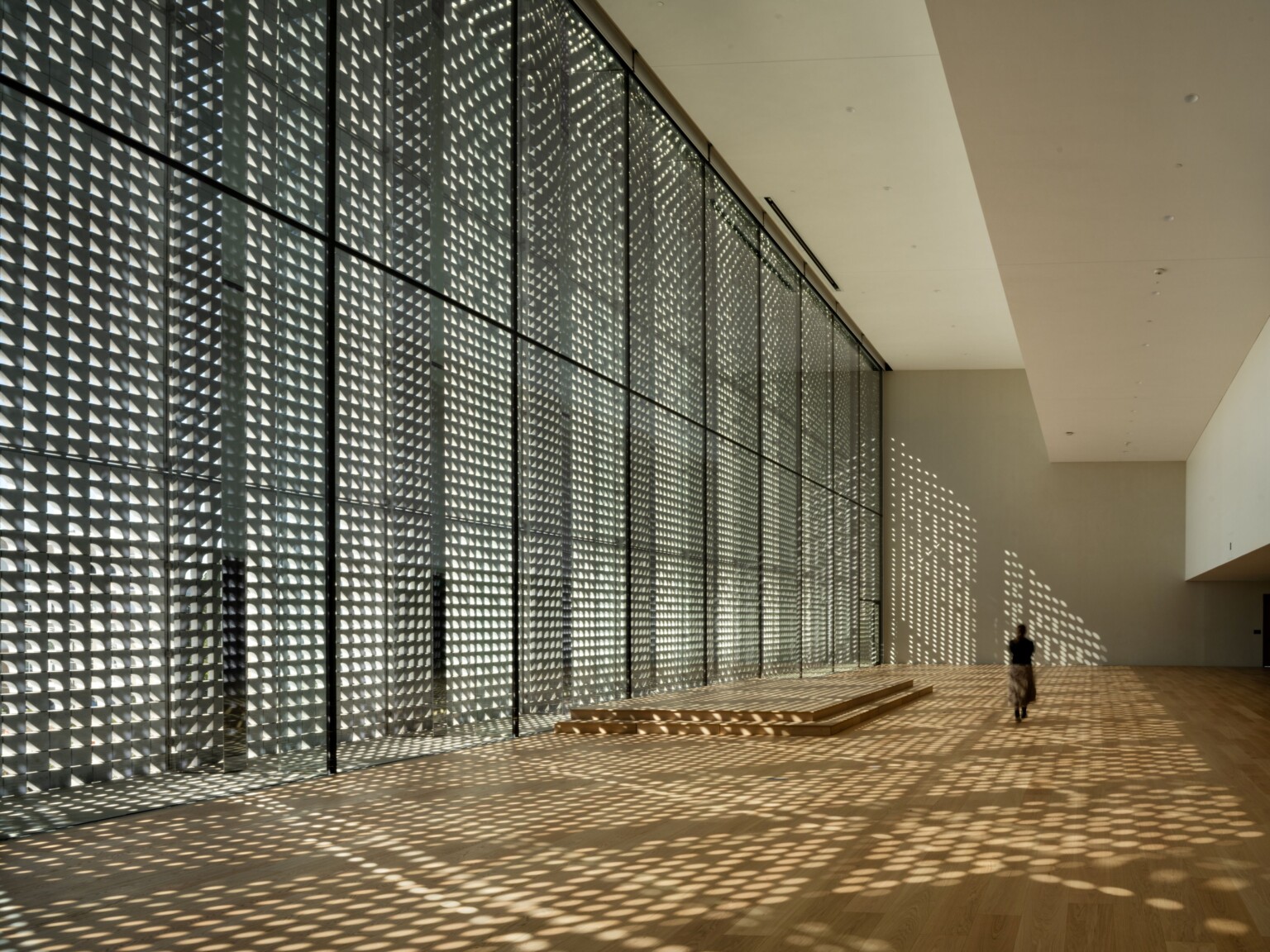 Photo by Nic Lehoux; Dappled light fills lobby of the United States first Ismaili Center; woman walks through the double height calming space