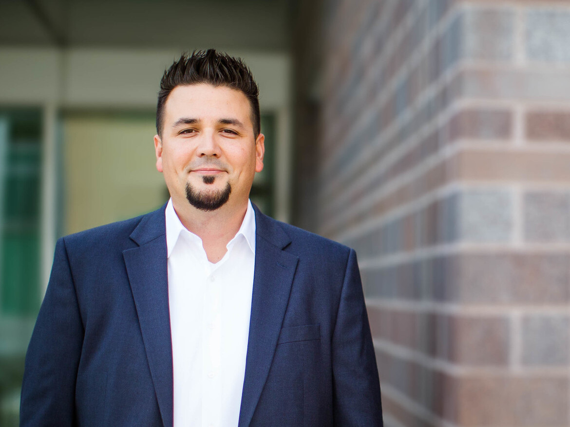 grinning man with facial hair and a casual suit