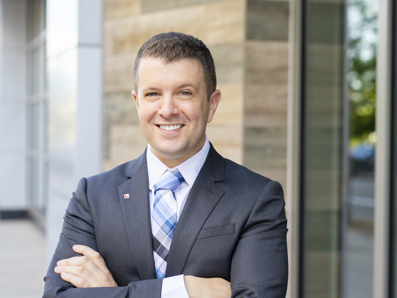 smiling professional man in a gray blazer with a blue plaid tie